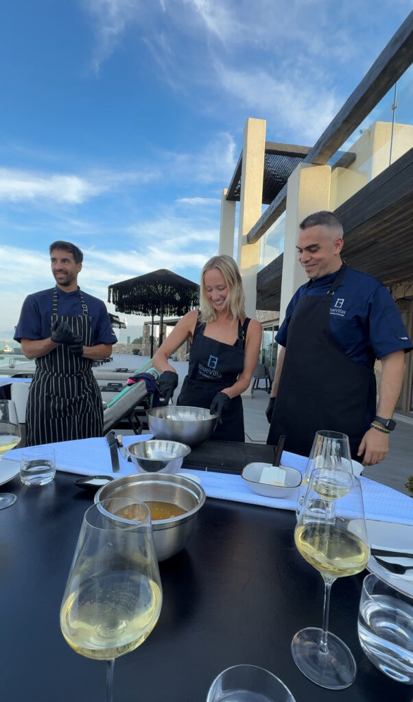 Outdoor Greek cooking class setup beside the pool at a private villa in Mykonos. Luxury travel itinerary for Mykonos and Paros